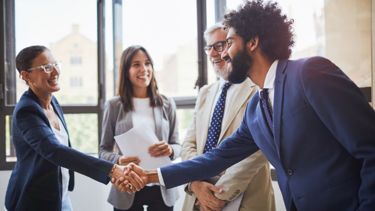 Two professionals shaking hands in a group meeting